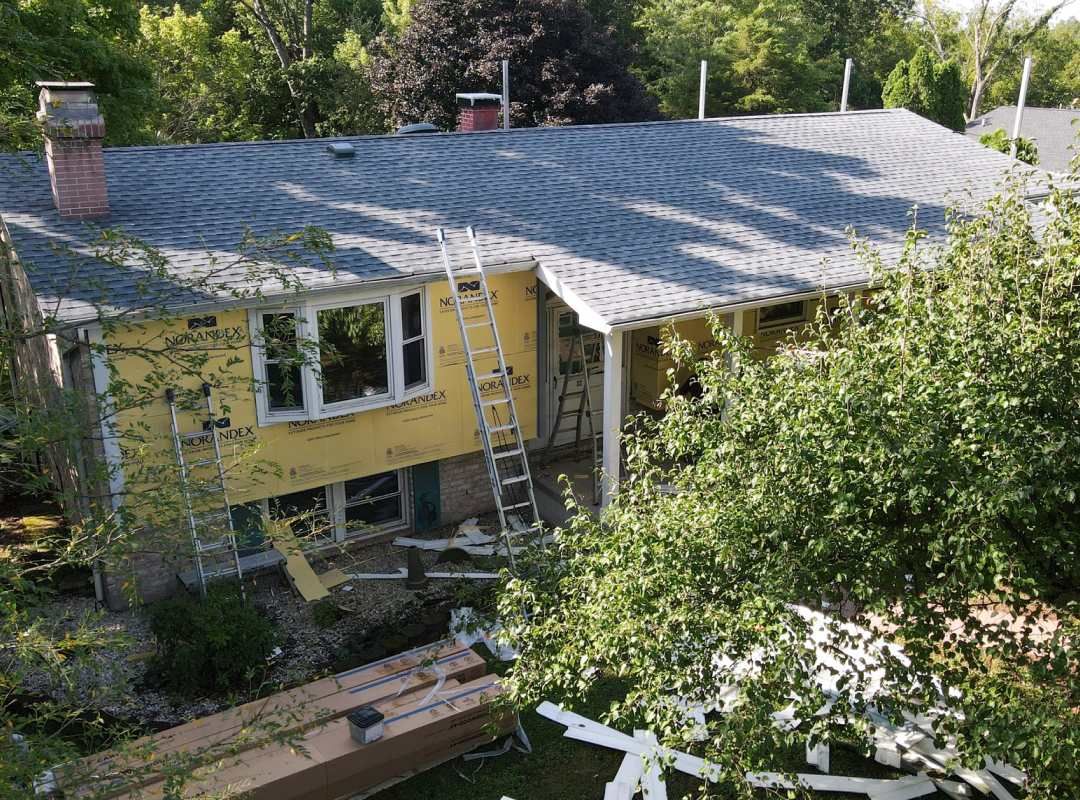 An aerial view of a house under construction with a roof being installed.