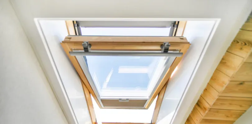 Looking up at a skylight in a room with a wooden ceiling.
