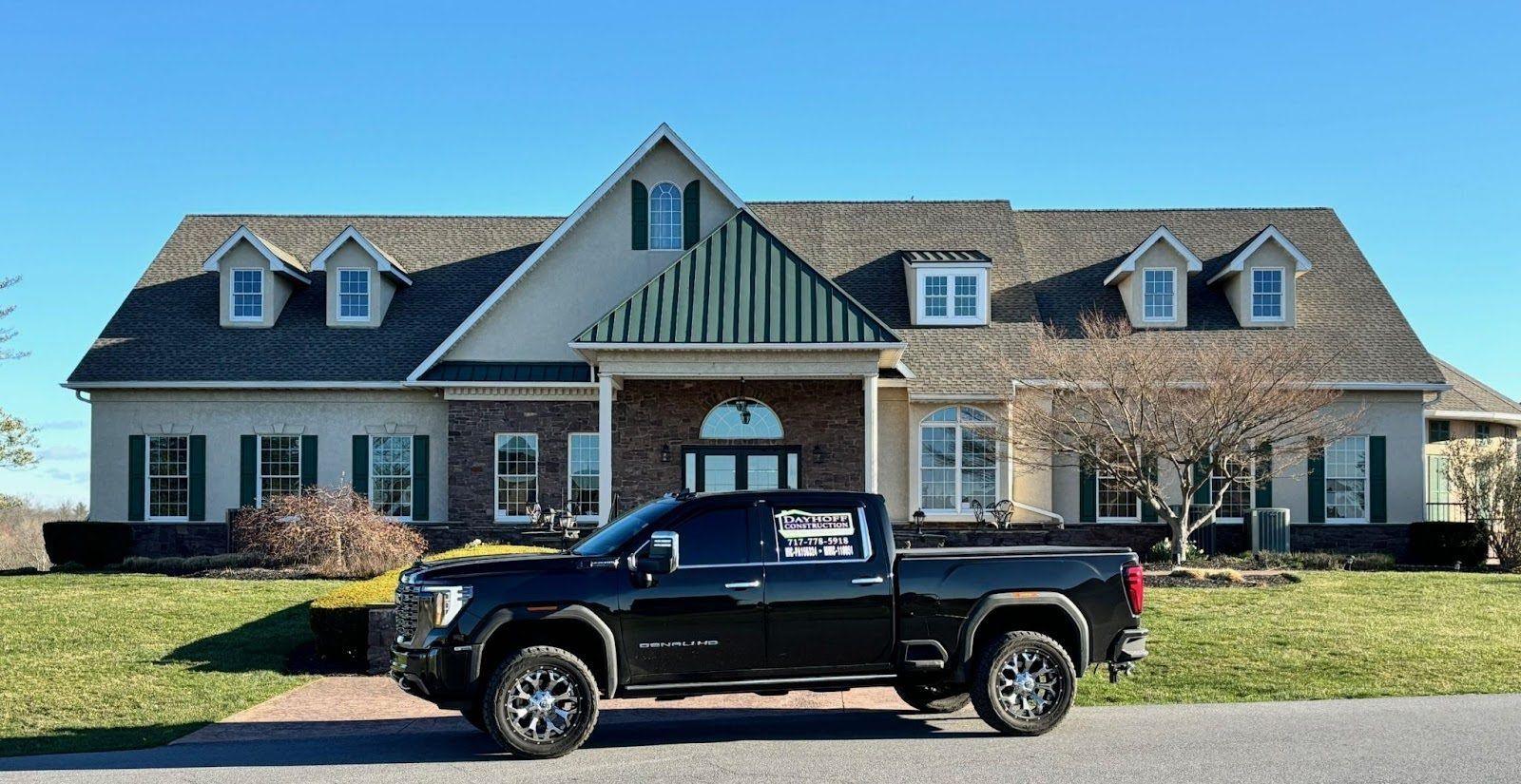 A black truck is parked in front of a large house.