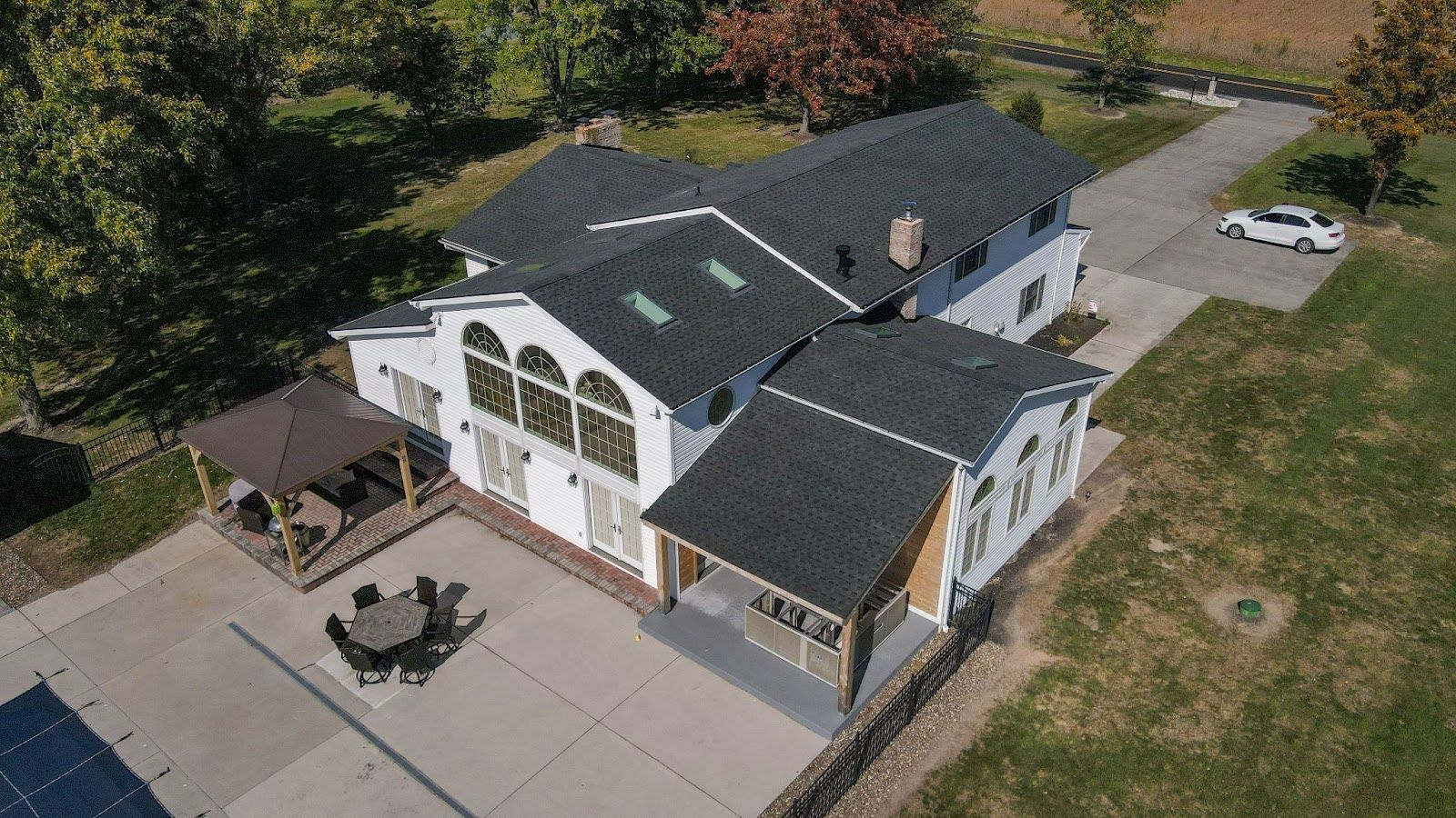 An aerial view of a large white house with a black roof.