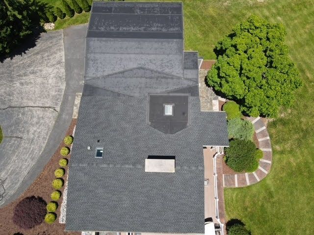 An aerial view of a house with a roof and a driveway.