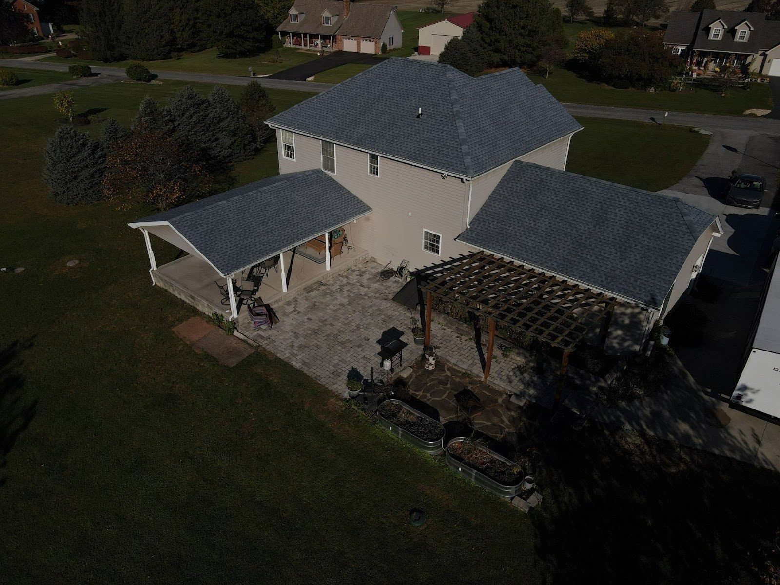 An aerial view of a house with a gray roof and a pergola.