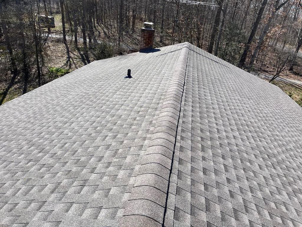 A roof with a chimney on top of it and trees in the background.