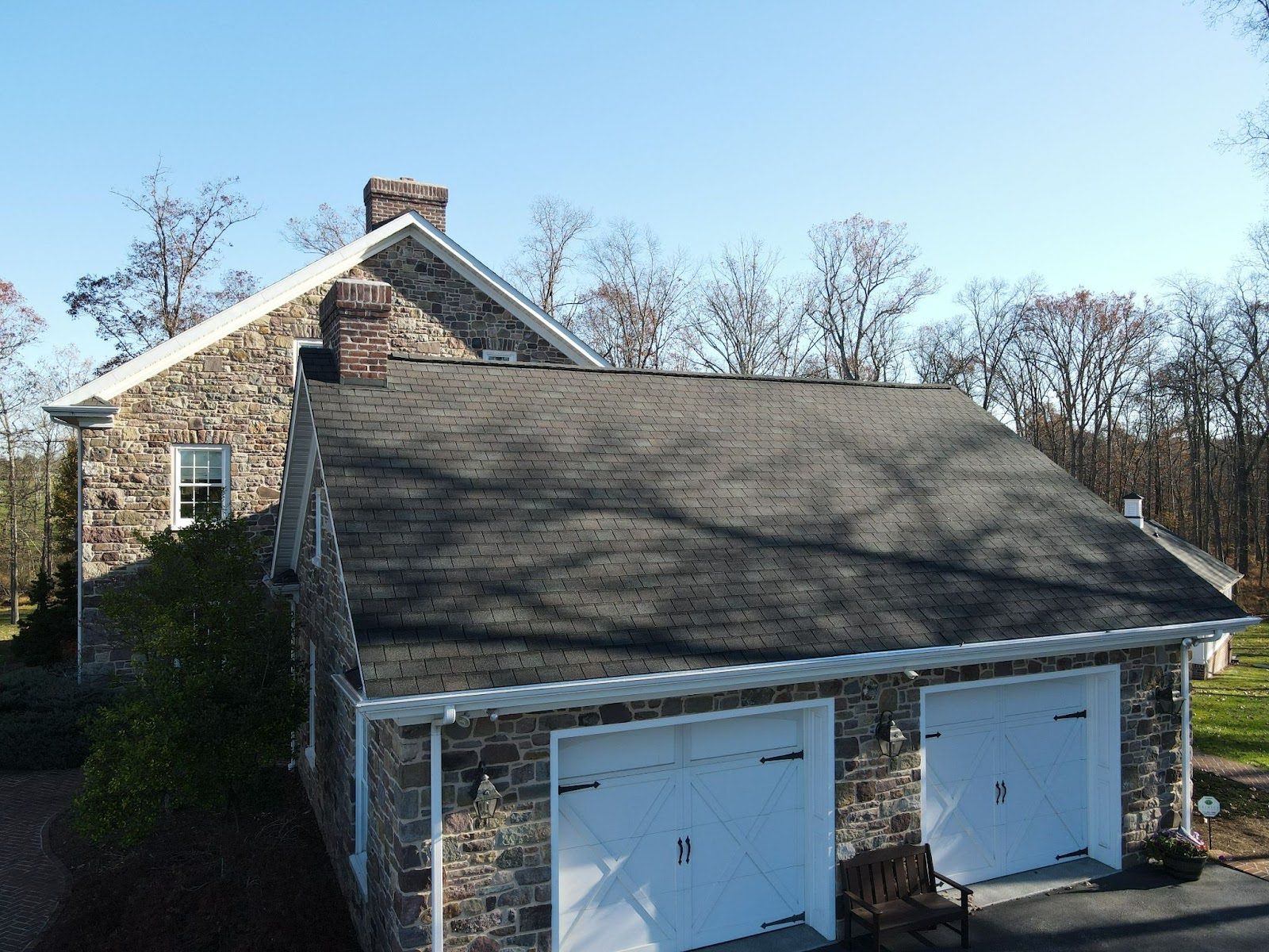 A stone house with two garage doors and a chimney