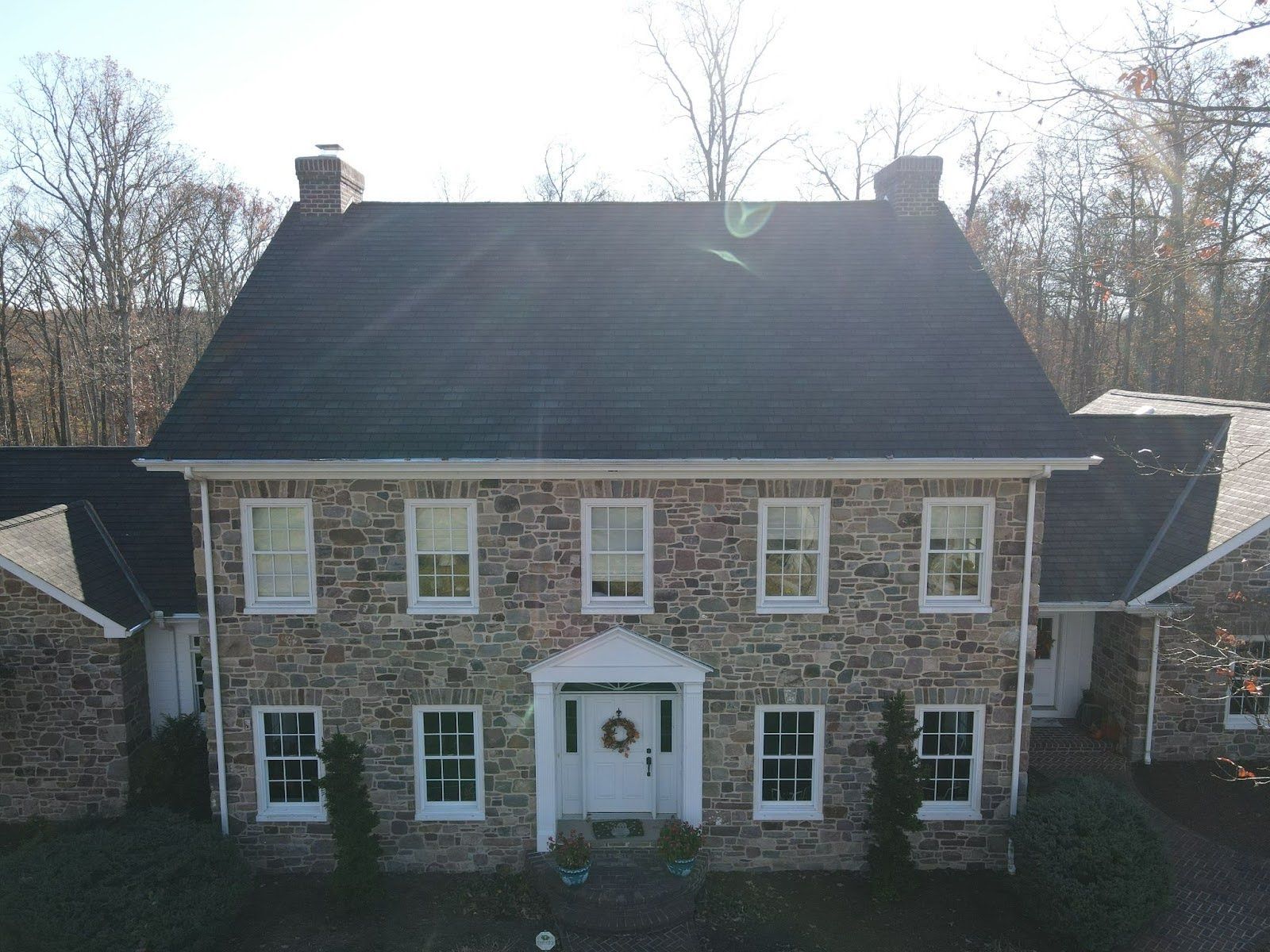 An aerial view of a large stone house with a black roof