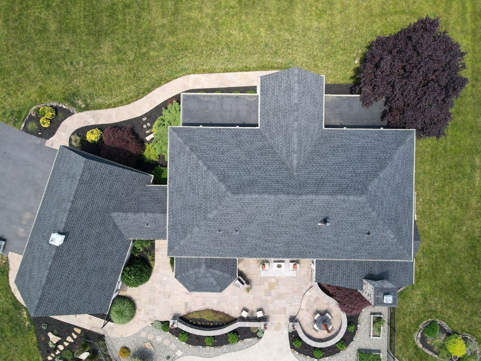 An aerial view of a large house with a roof and a driveway.