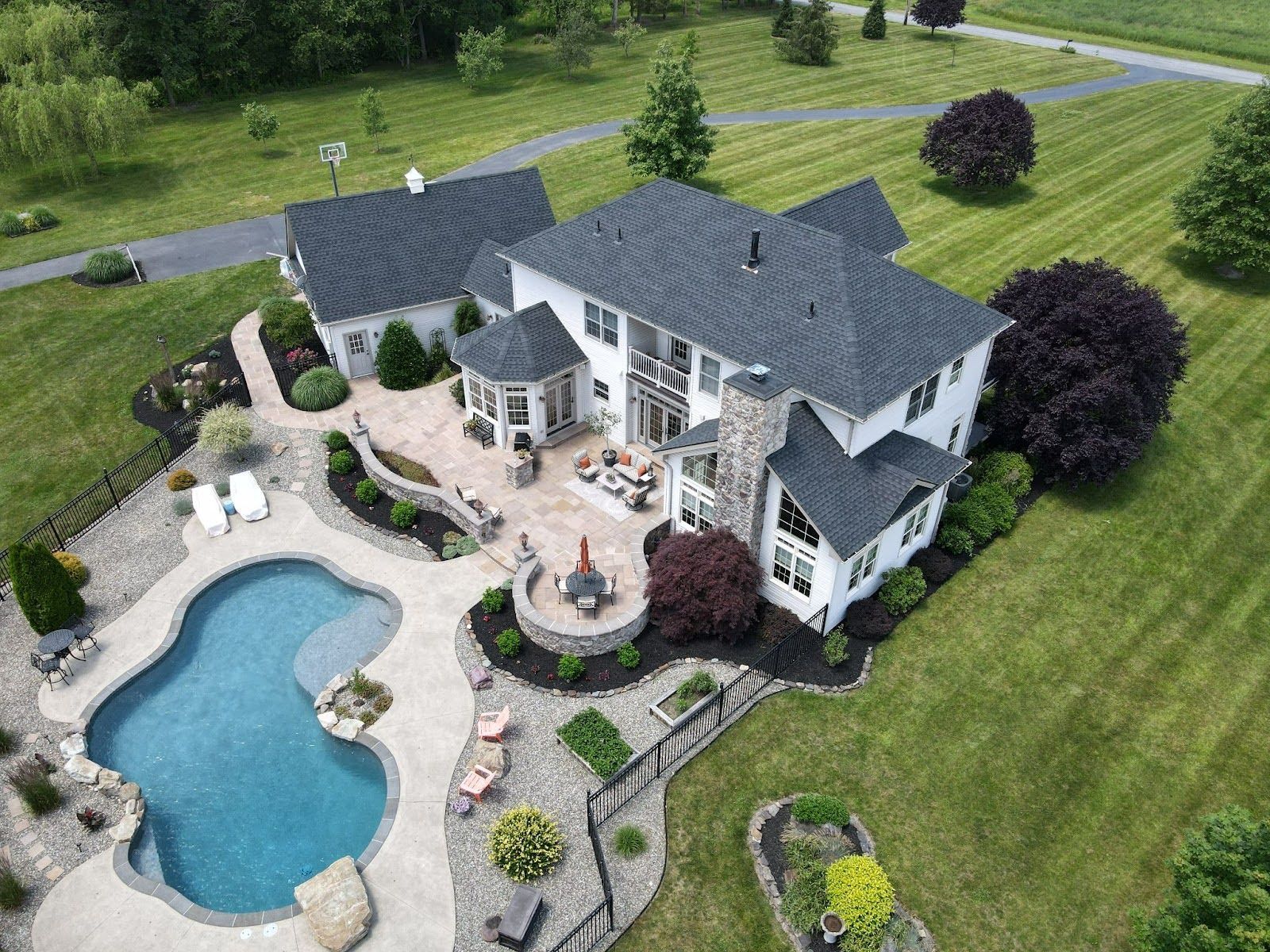 An aerial view of a large house with a large pool in the backyard.