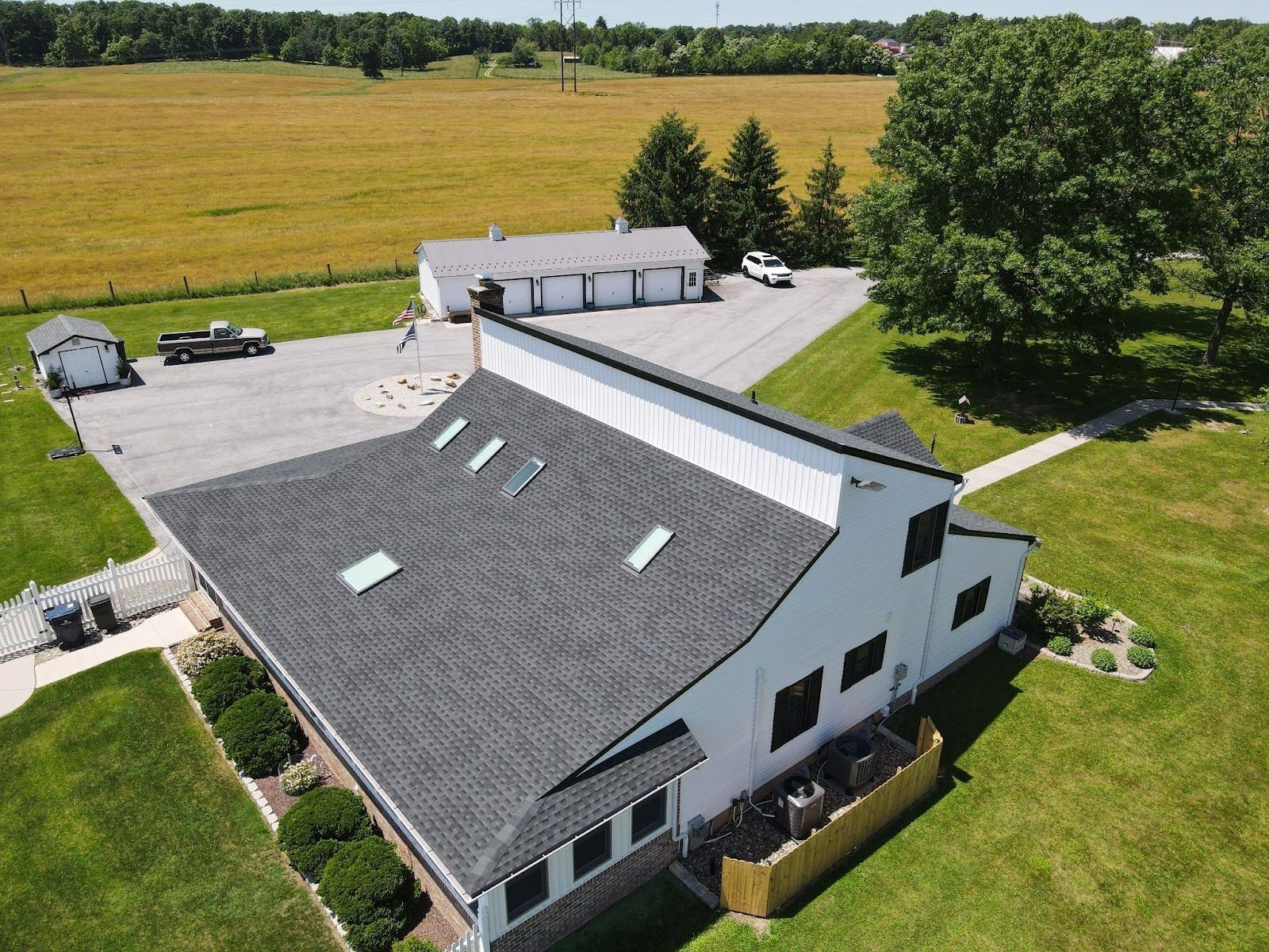 An aerial view of a white house with a gray roof