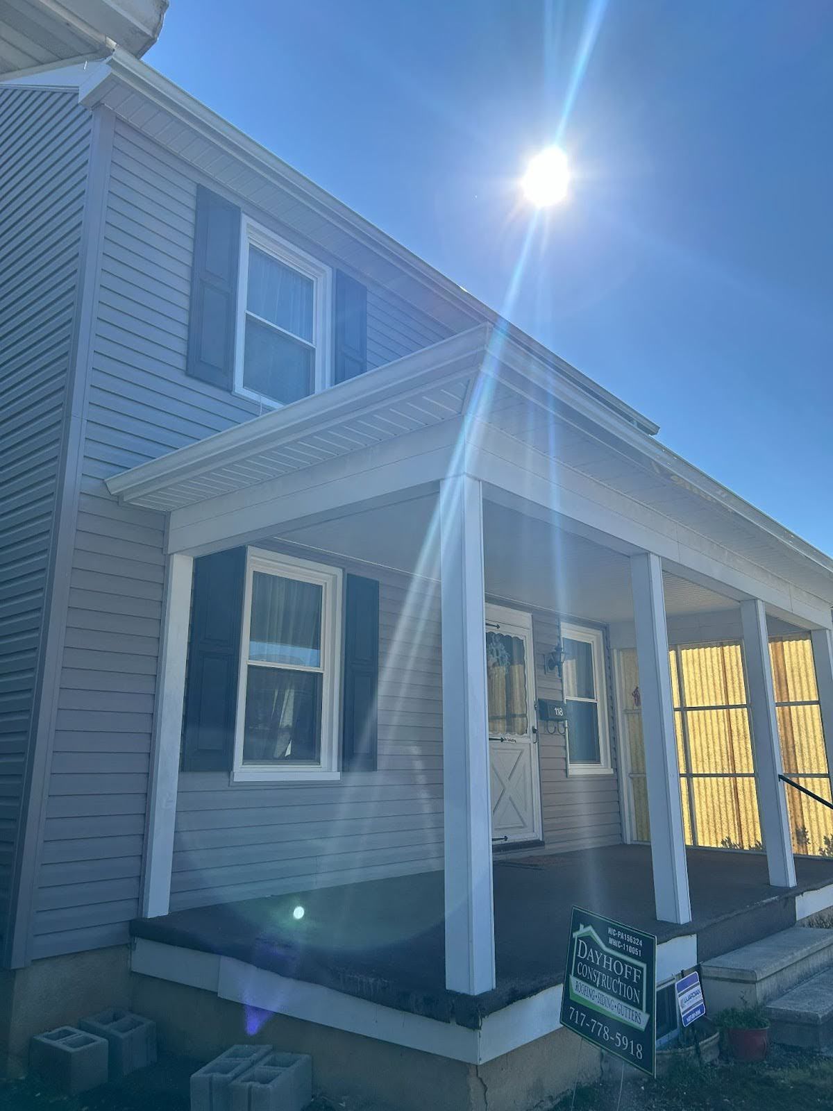 A house with a porch and a blue sky in the background.