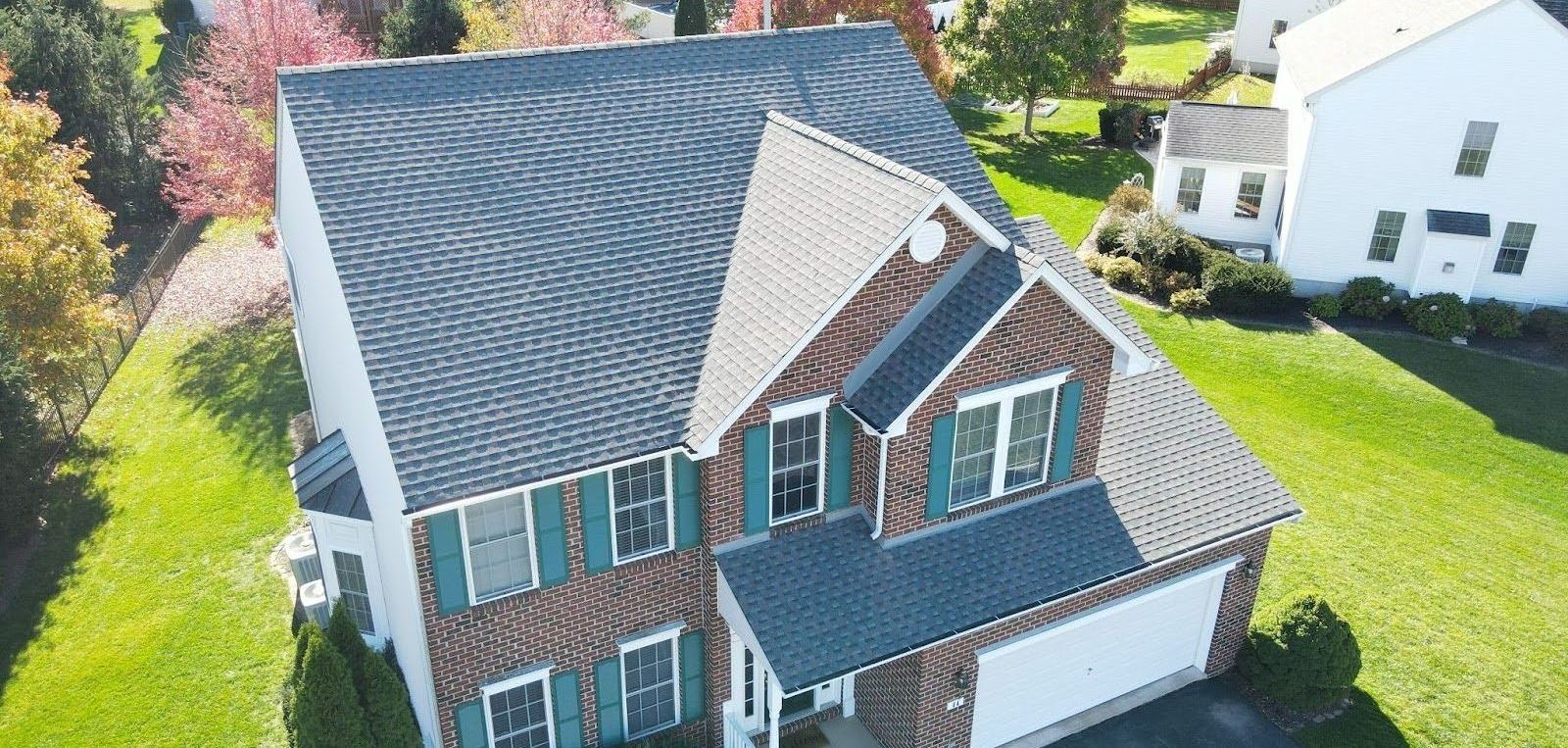 An aerial view of a brick house with a new roof.