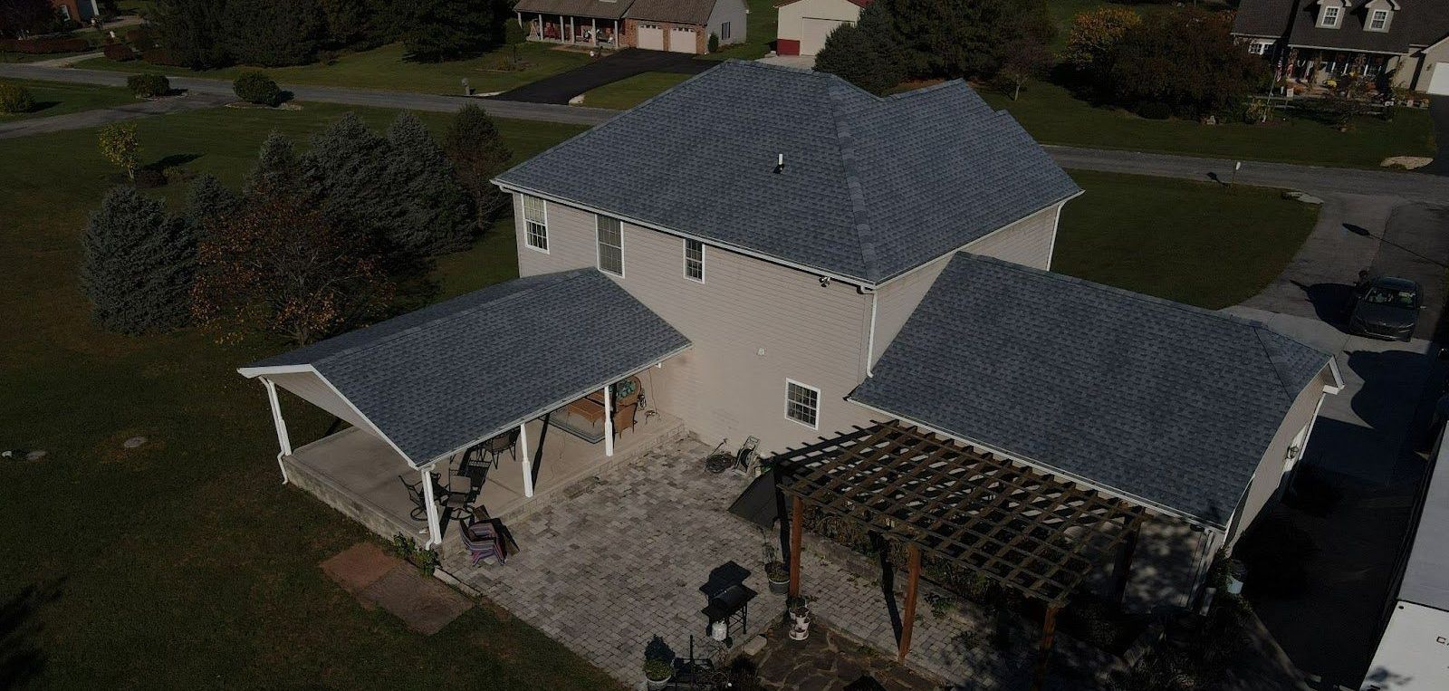 An aerial view of a house with a gray roof and a pergola.