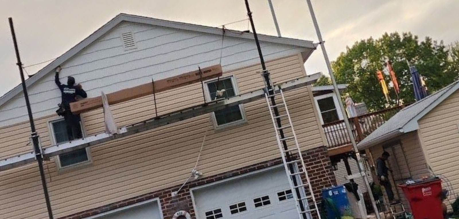 A man is standing on a scaffolding on the side of a house.