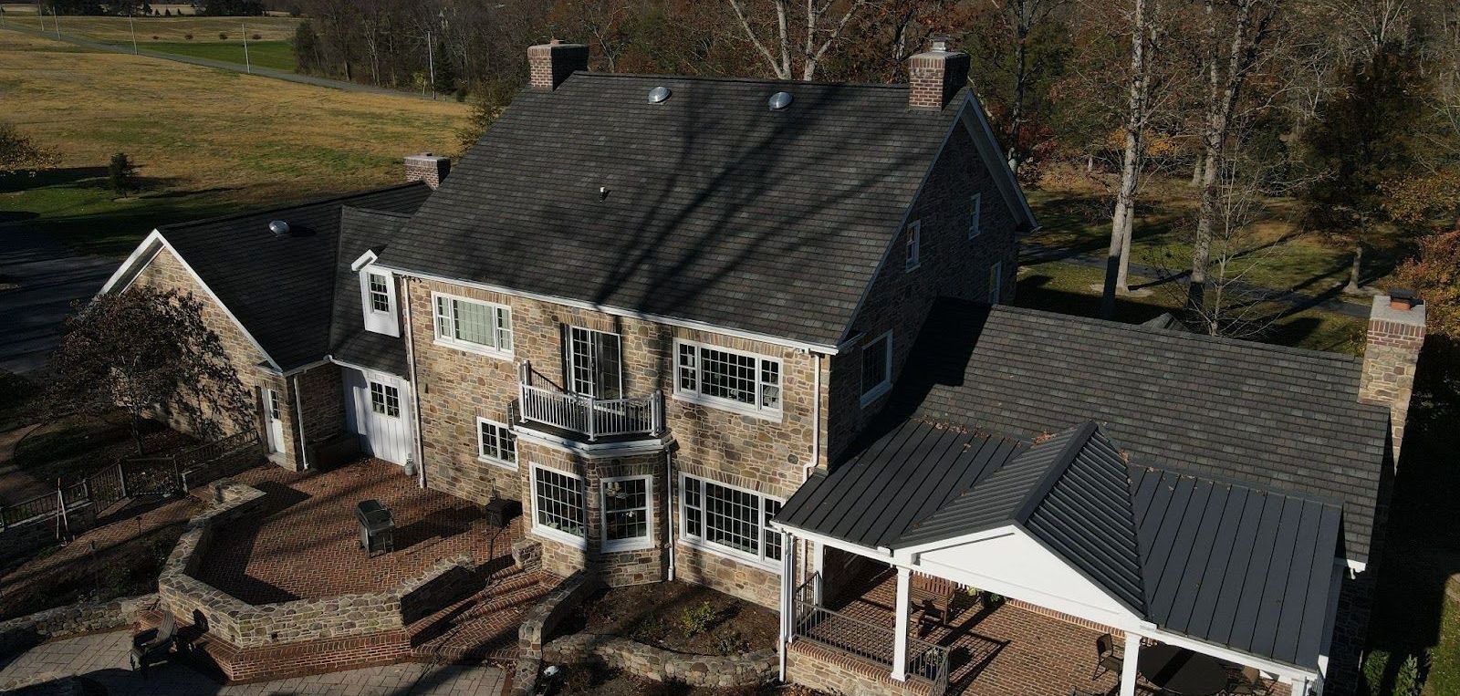 An aerial view of a large stone house with a black roof.