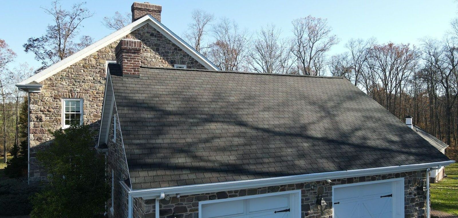 A stone house with a garage and a chimney on the roof.