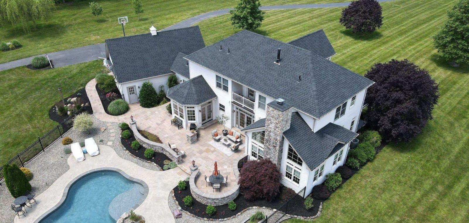 An aerial view of a large house with a pool in the backyard.