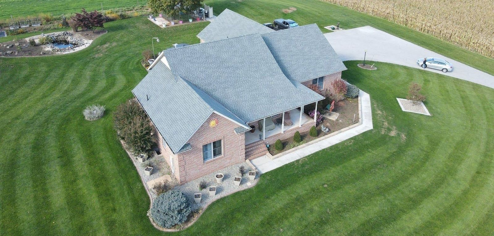 An aerial view of a large house with a lush green lawn.