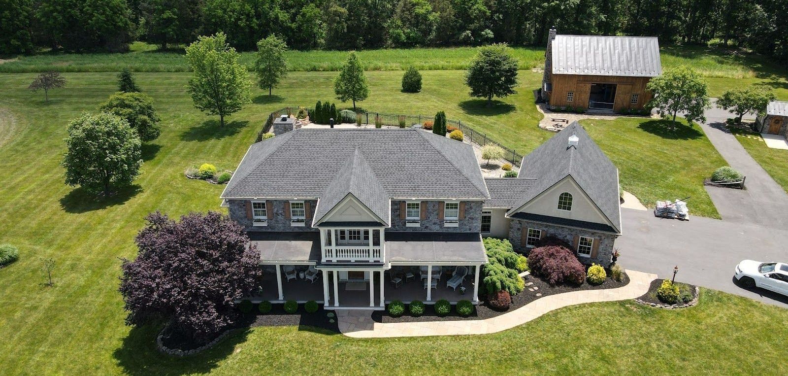 An aerial view of a large house in the middle of a lush green field.