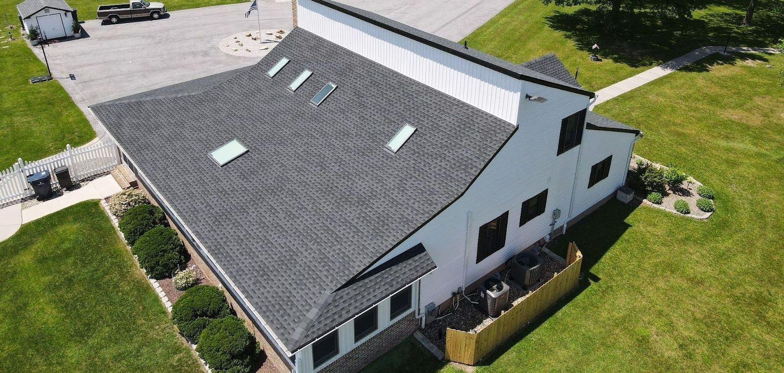An aerial view of a white house with a black roof.