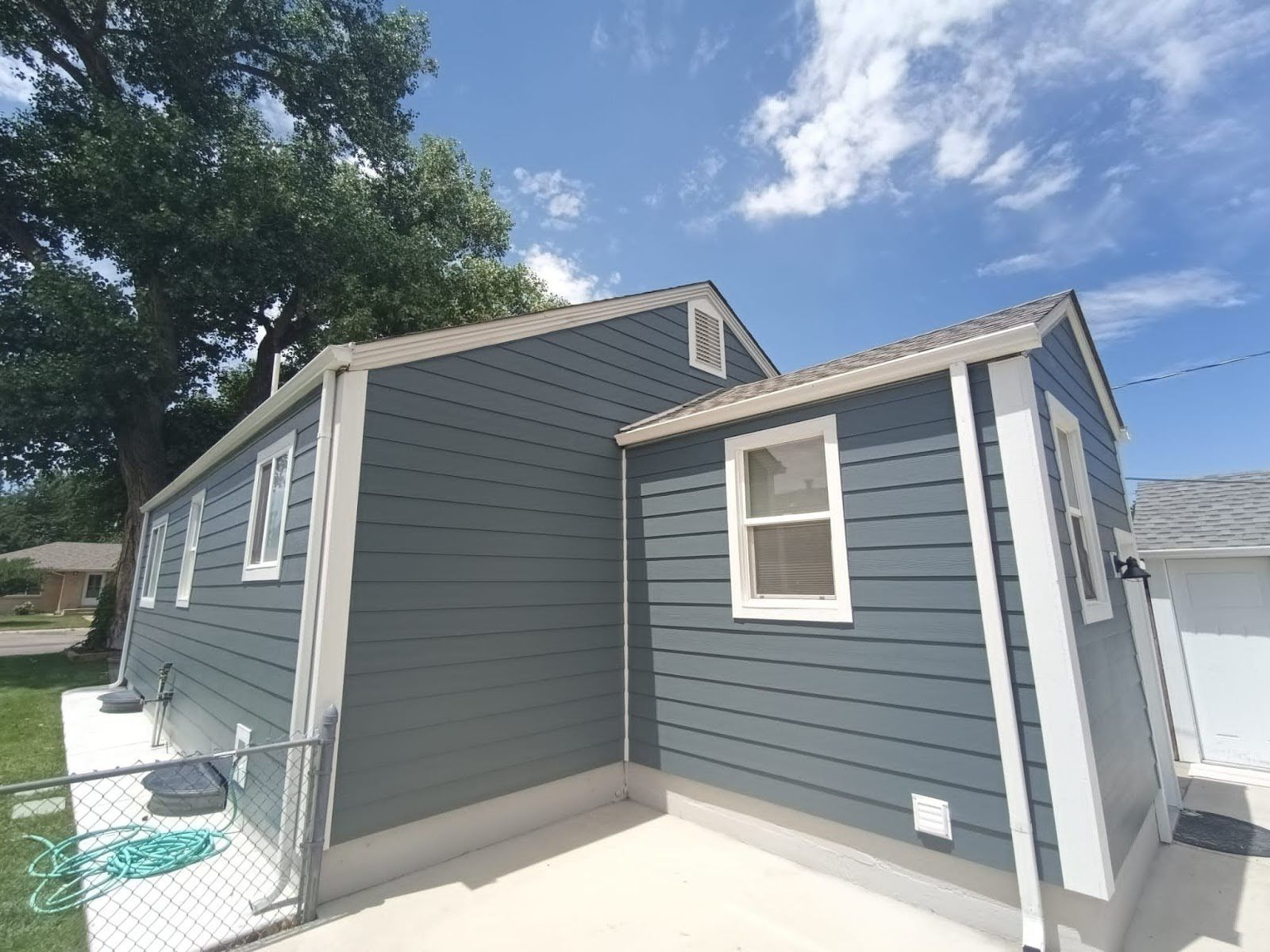 A gray house with white trim and a fence in front of it