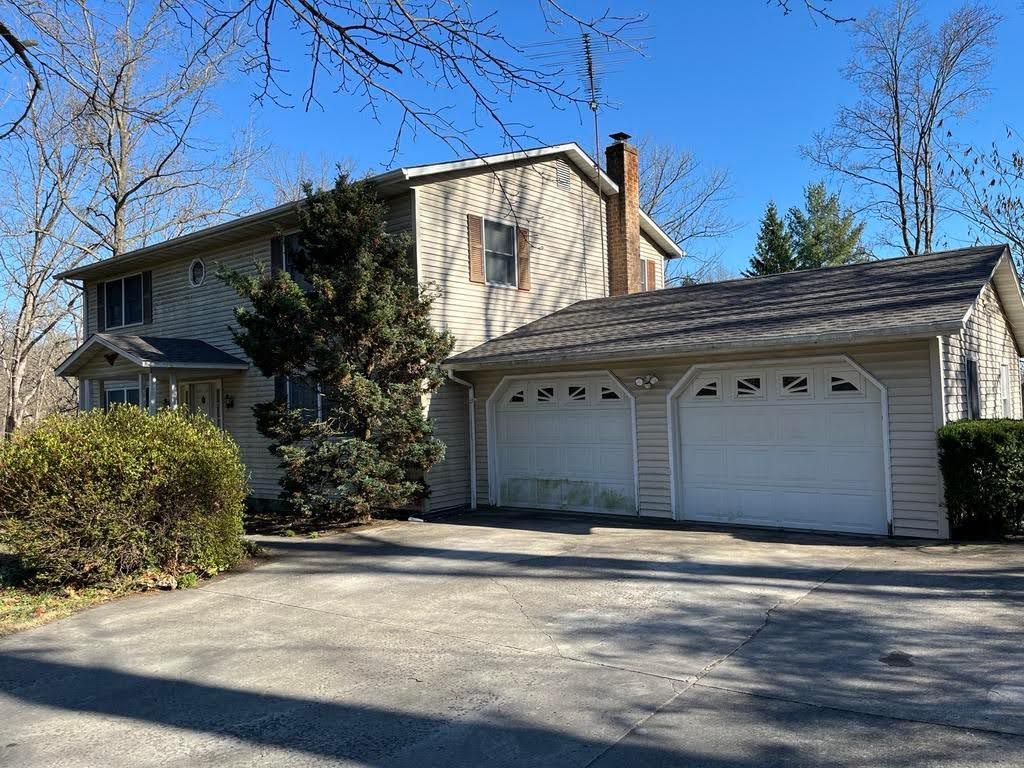 A house with two garage doors and a driveway in front of it.