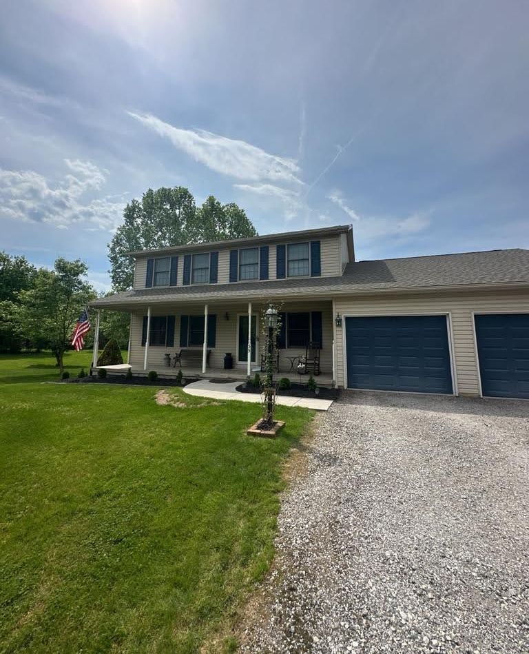 A house with two garage doors and a porch on a sunny day.