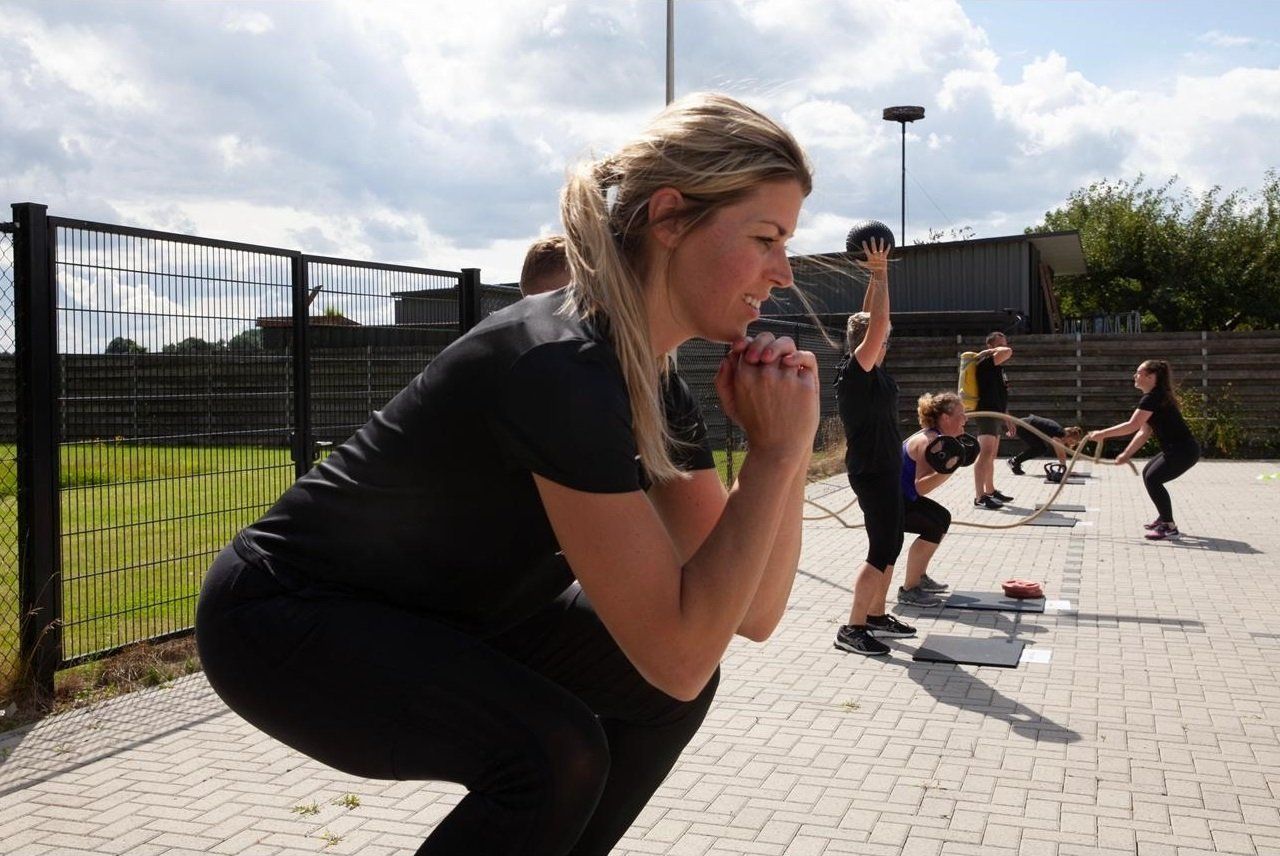 Een groep mensen doet squats in een park.