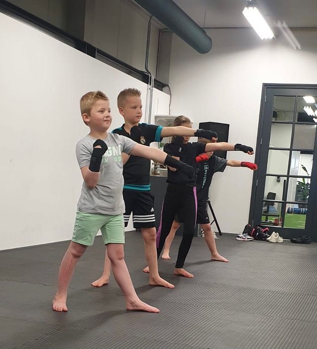 Een groep jonge jongens beoefent vechtsporten in een sportschool