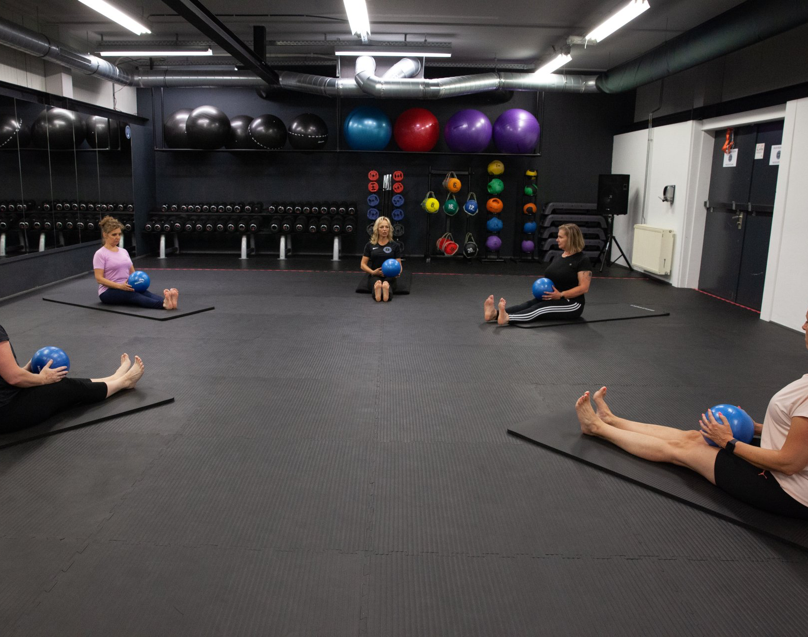 Een groep mensen zit op yogamatten in een sportschool.