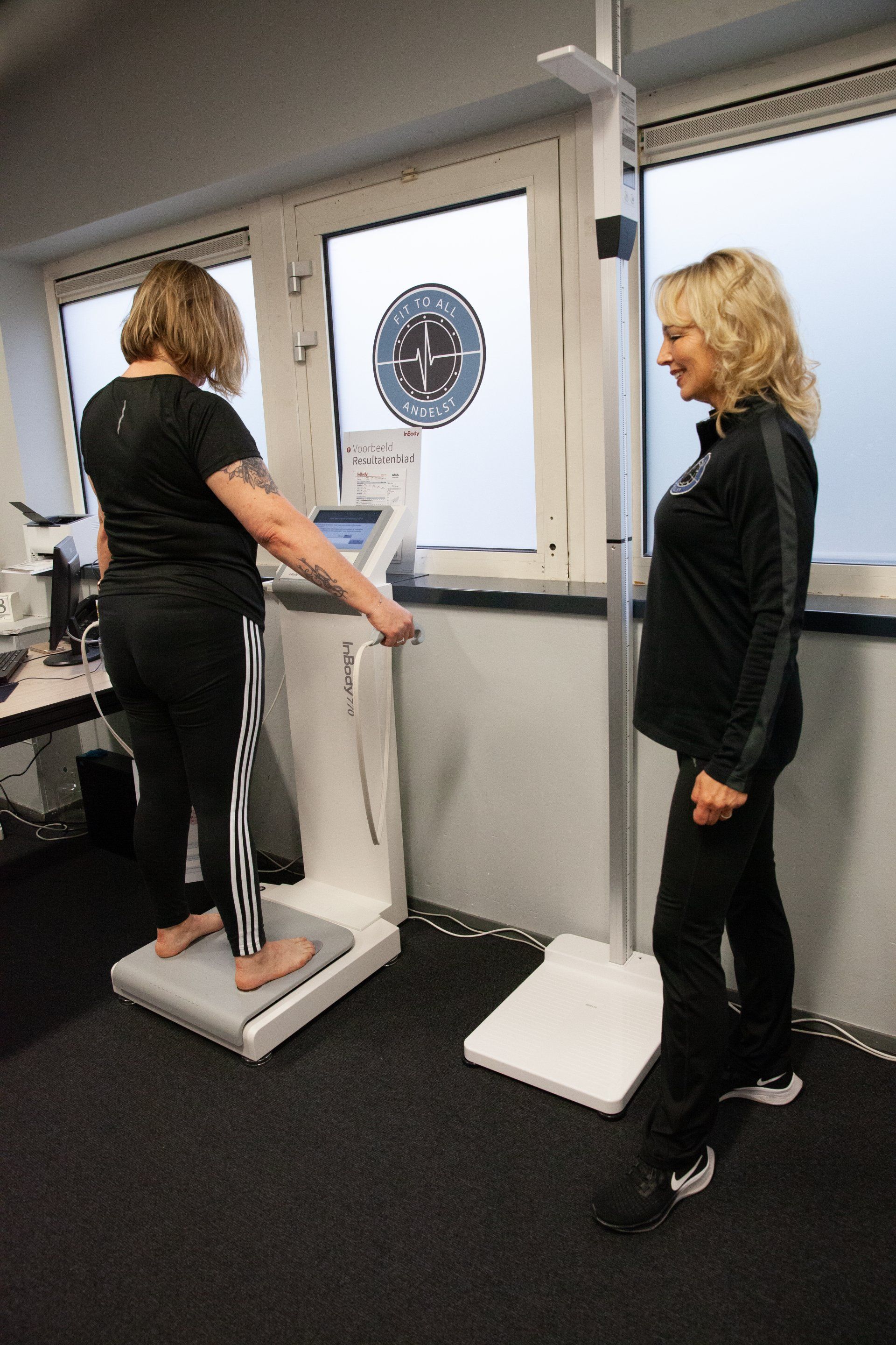 Twee vrouwen staan ​​naast elkaar voor een machine.