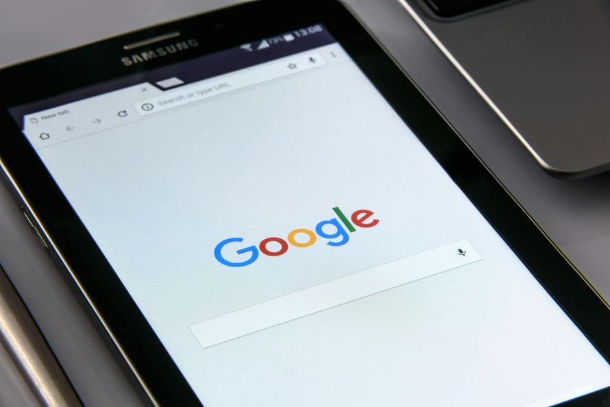 Tablet displaying the Google search page. Chrome browser, white background, Google logo in colors.