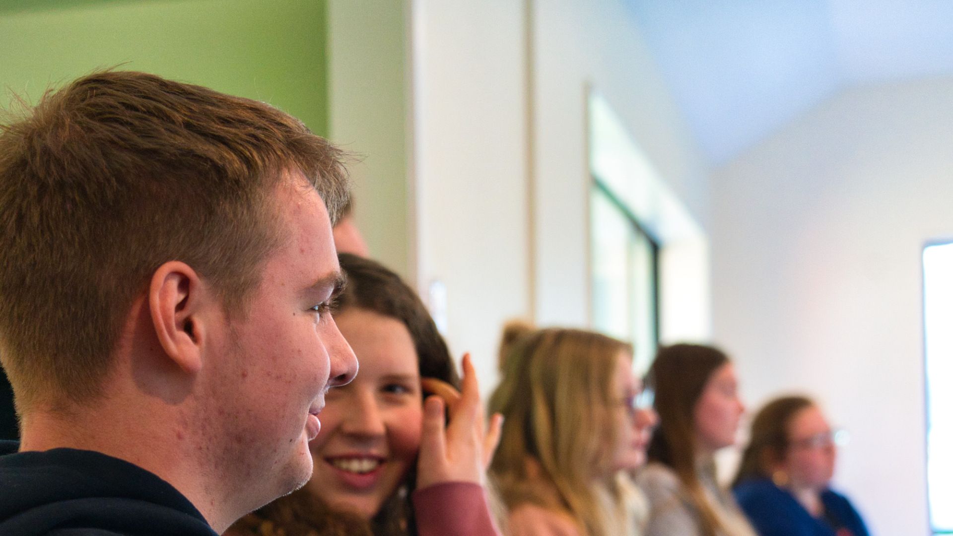 A group of people are sitting in a row in a room.