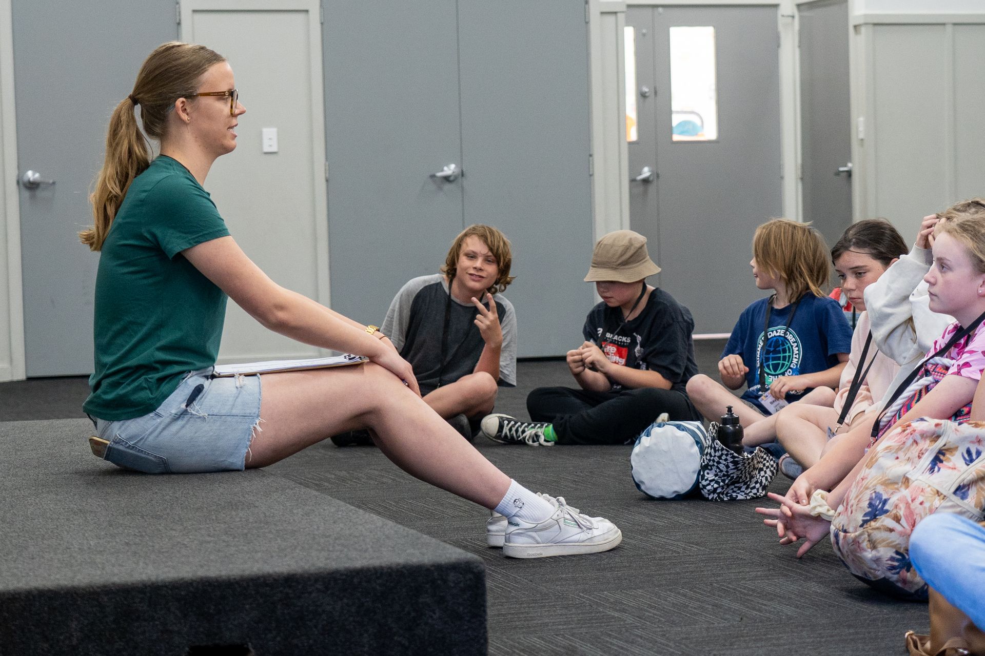 instructions being given to a group of children who are sitting on the floor