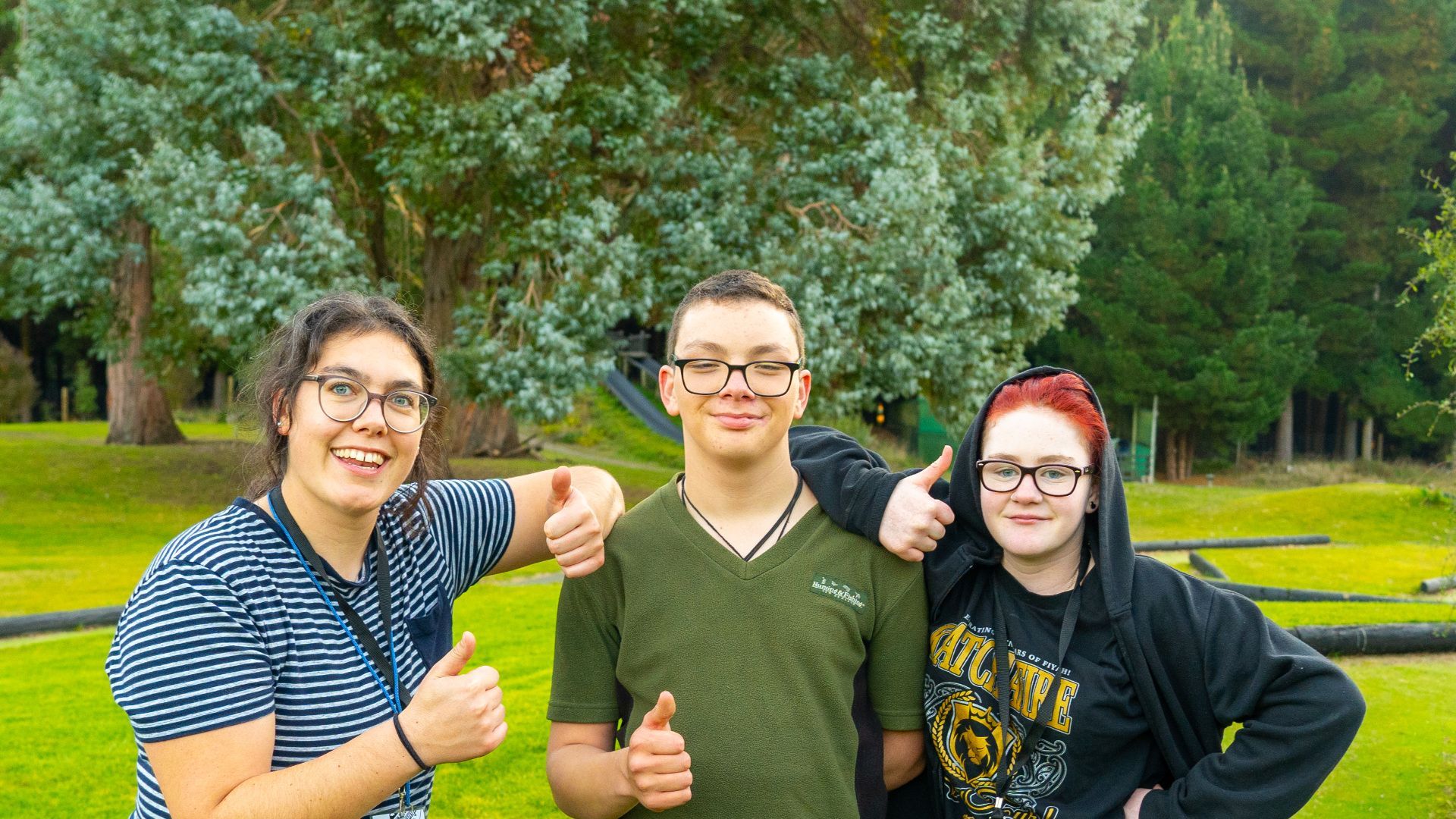 Three people smiling with their thumbs up