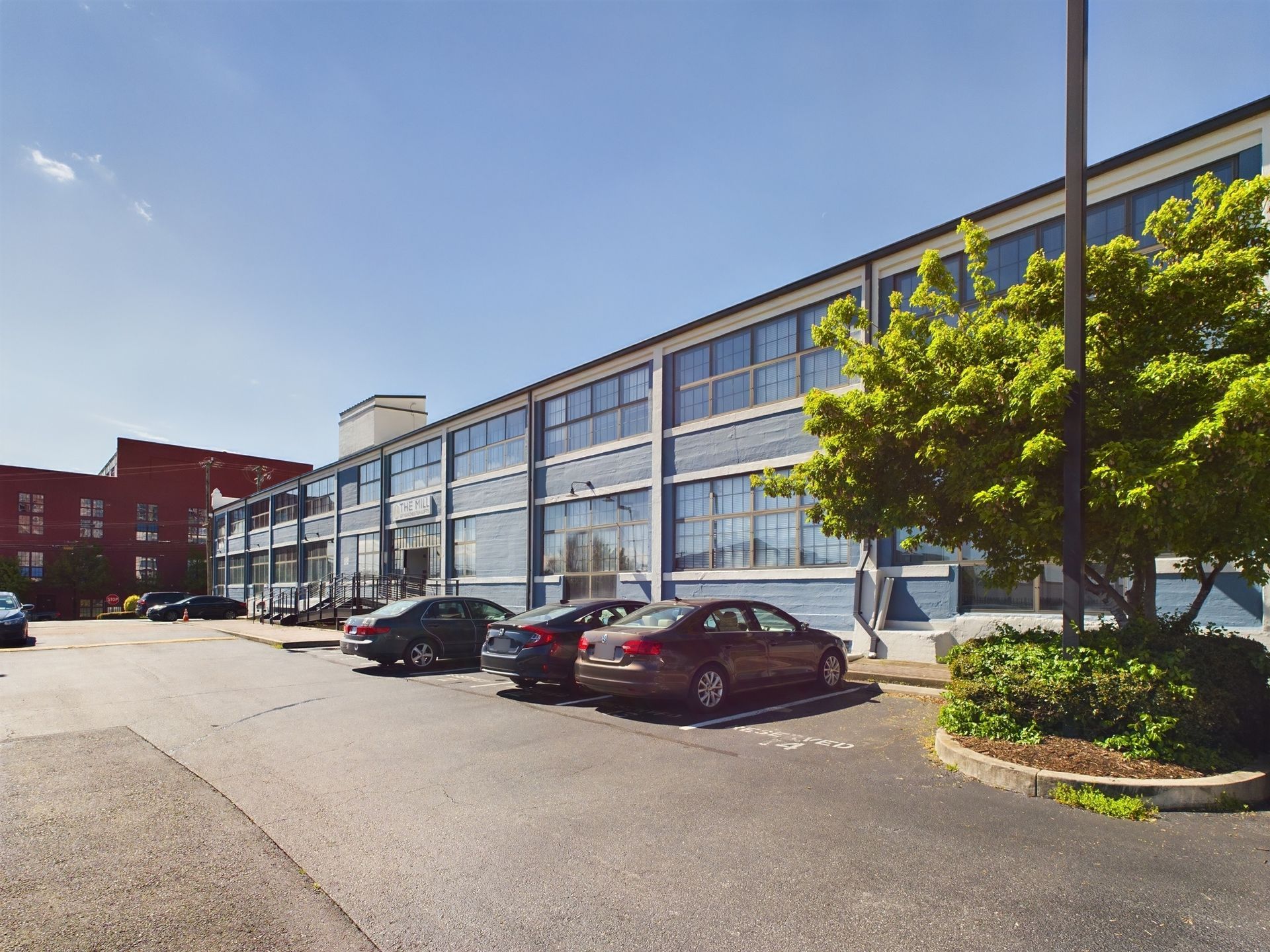A parking lot in front of a large building with cars parked in front of it.