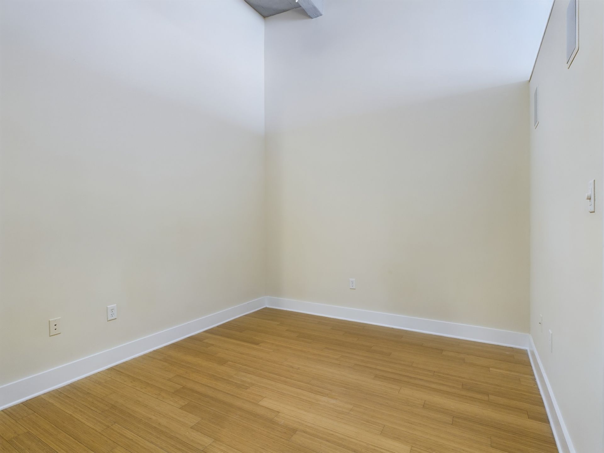 An empty room with hardwood floors and white walls.