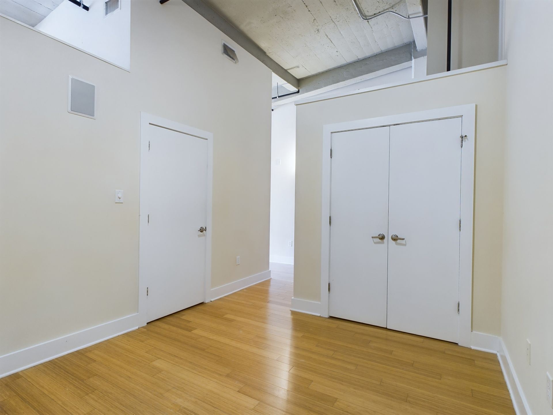 An empty room with hardwood floors and white doors