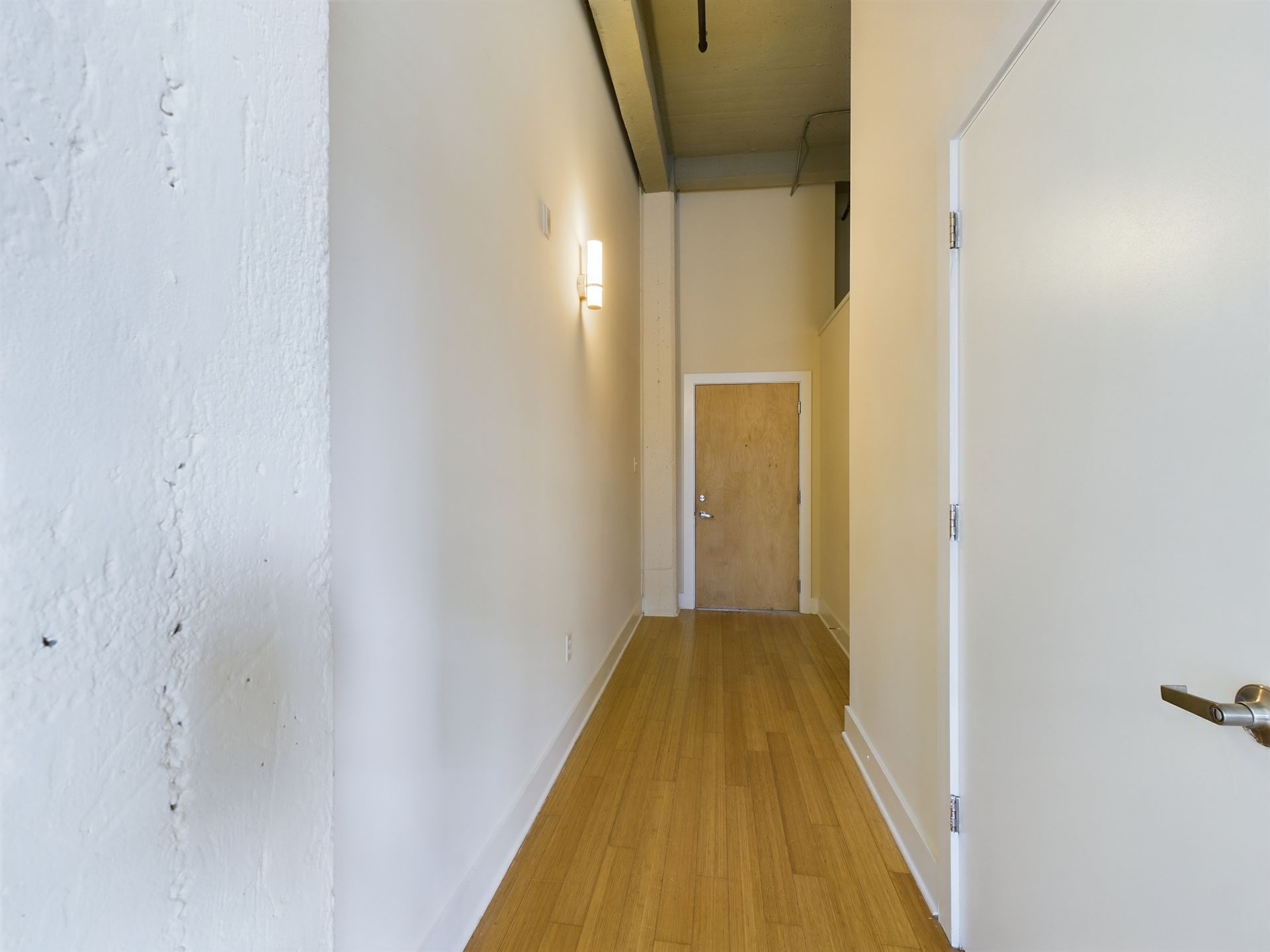A long hallway with wooden floors and white walls