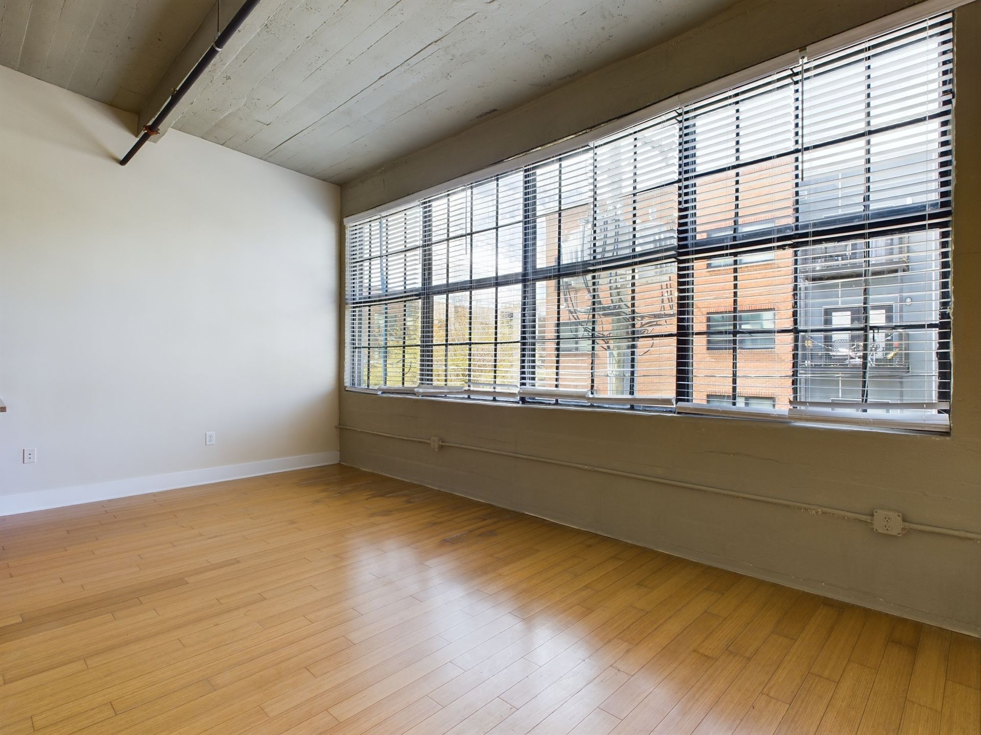 An empty room with a large window and blinds