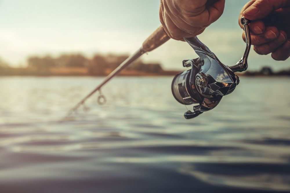 A person is holding a fishing rod and reel over a body of water.