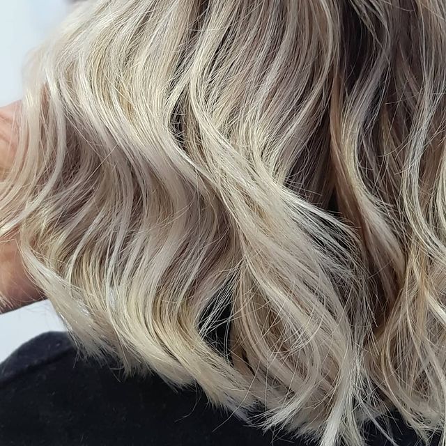 Balayage di capelli medio lunghi color bianco platino freddo con piega a onde