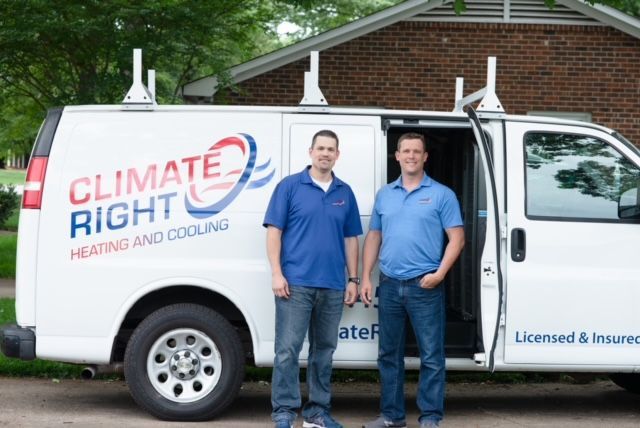 Two men are standing in front of a climate right van.