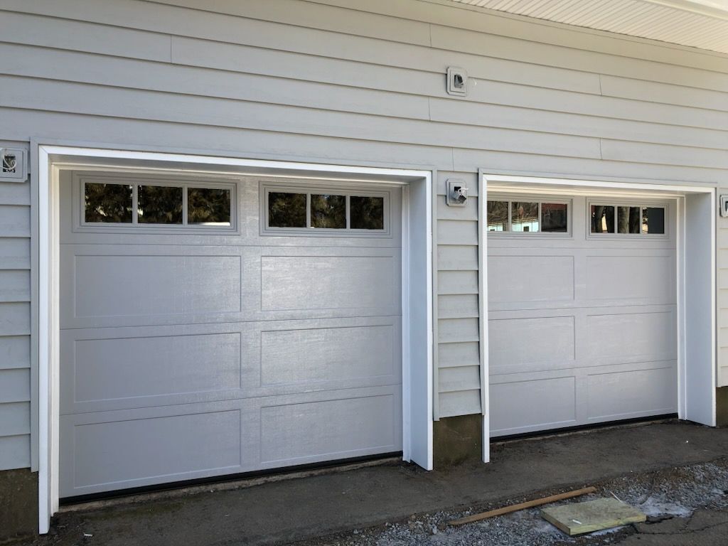 A row of white garage doors on a white house
