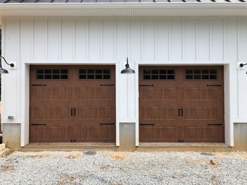 There are two garage doors on the side of a house.