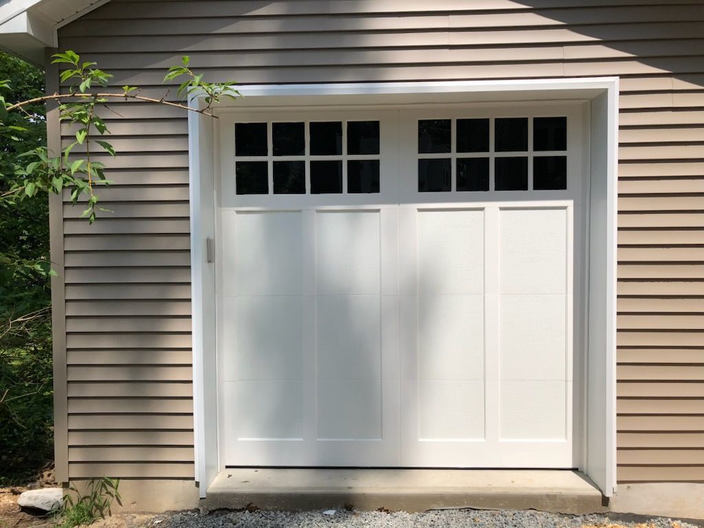 A white garage door is on the side of a house.