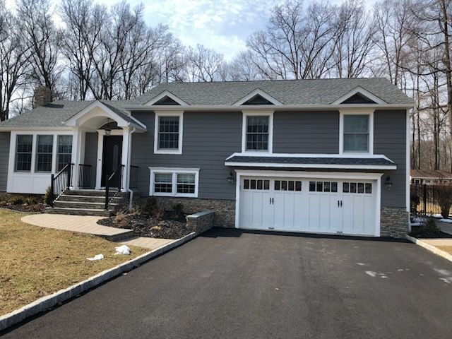 A large grey house with a white garage door