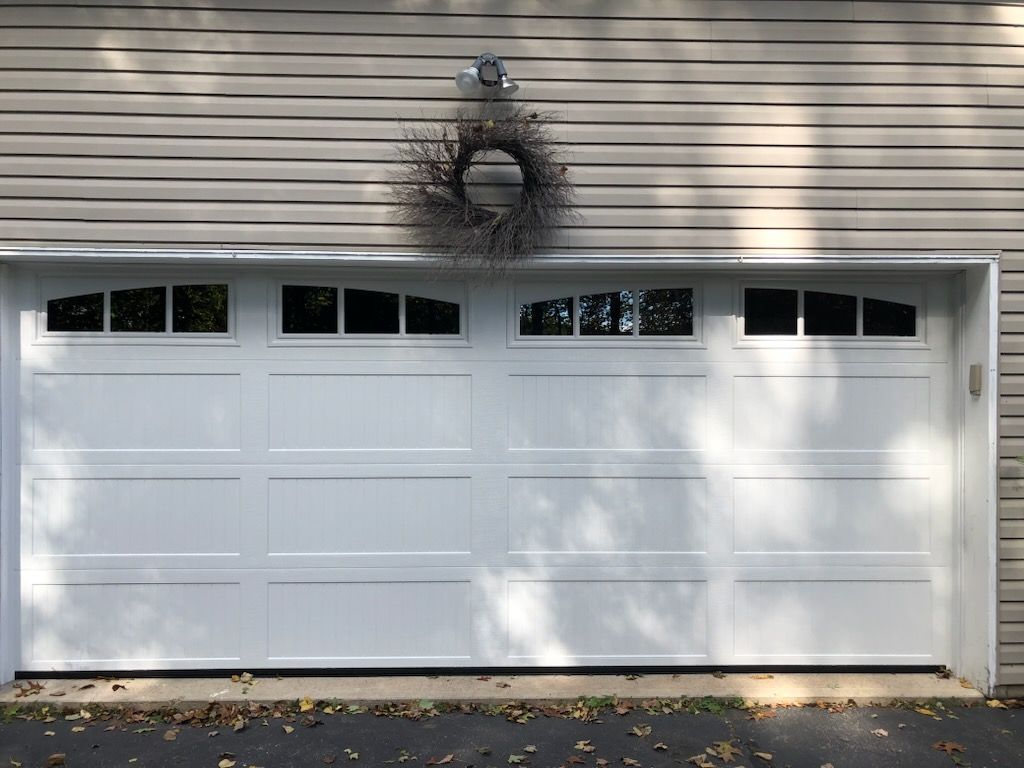 A white garage door with a wreath on top of it