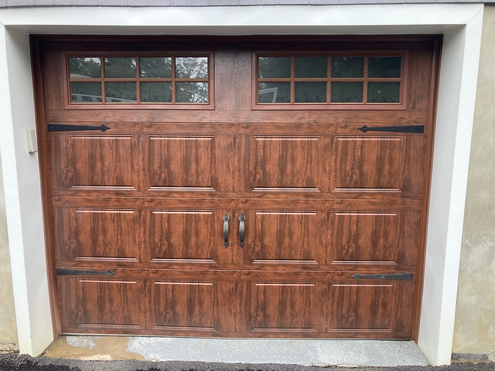 A wooden garage door with a window on the side of a house.