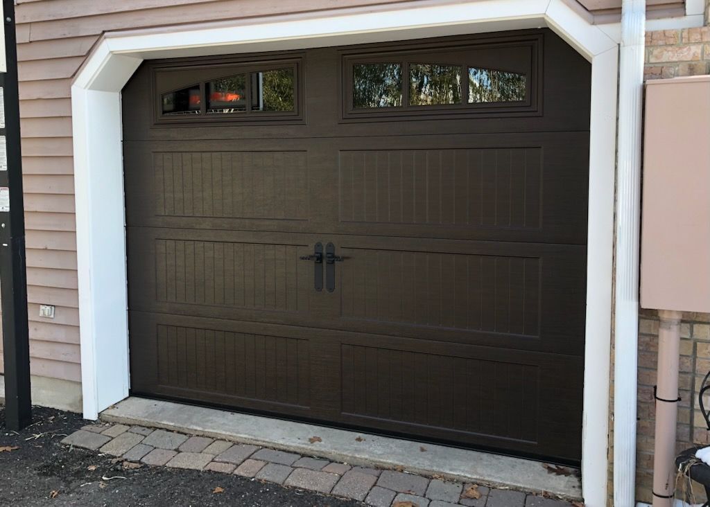 A brown garage door with a window on the side of a house.