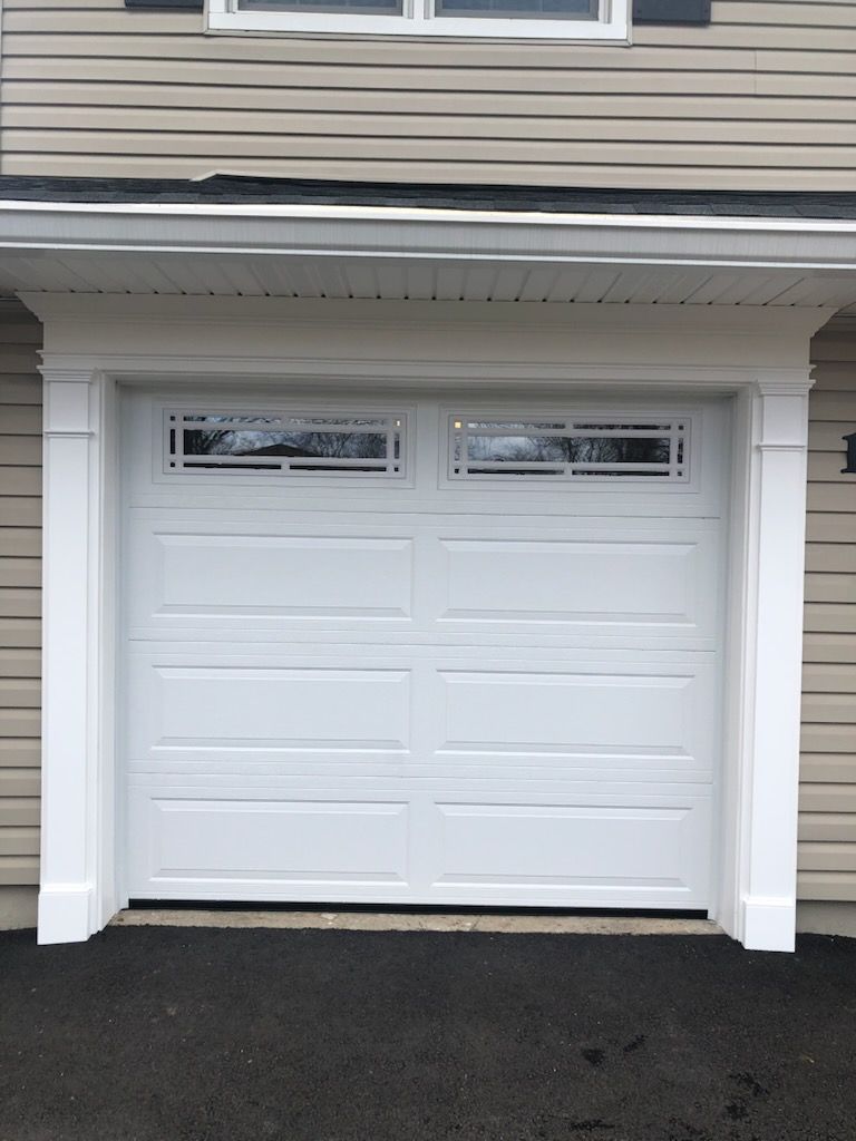 A white garage door with a window on the side of a house.