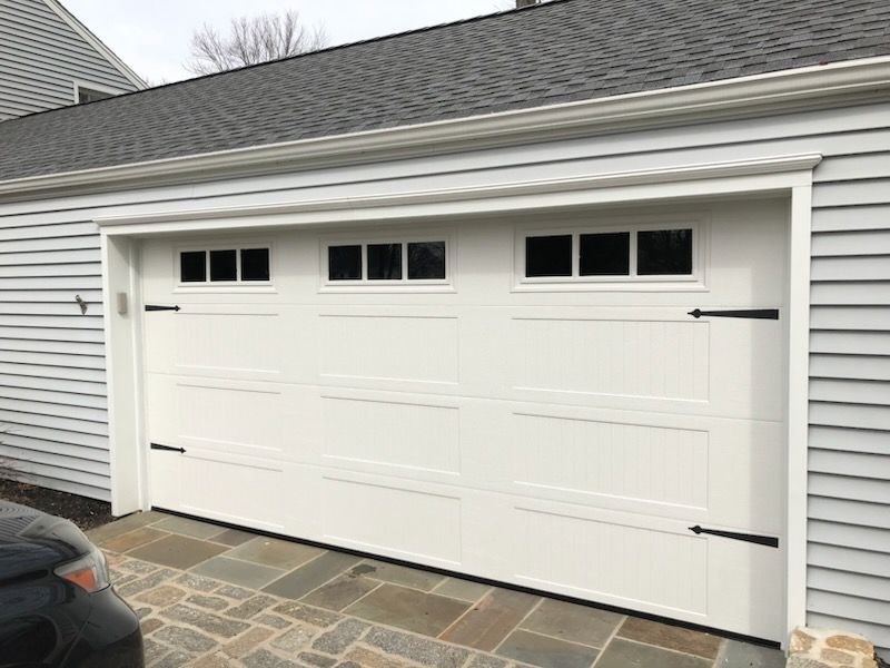 A white garage door with a black car parked in front of it.